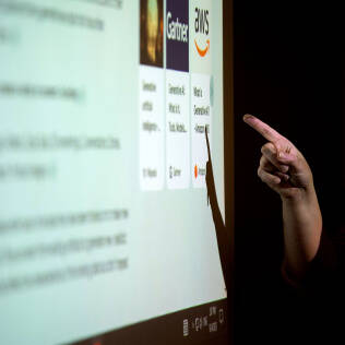 A person is pointing at a projected screen displaying various icons and text about generative AI